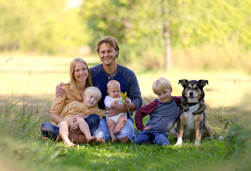 快乐的幸福年轻家庭和宠物狗的户外拍摄