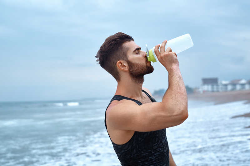 海边的男子在锻炼后喝水