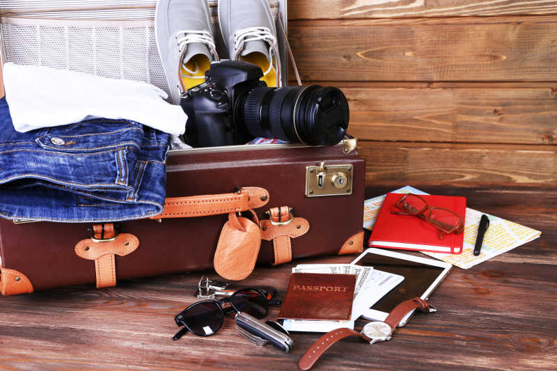 木板上的行李箱和望远镜鞋子衣服手表钥匙以及护照