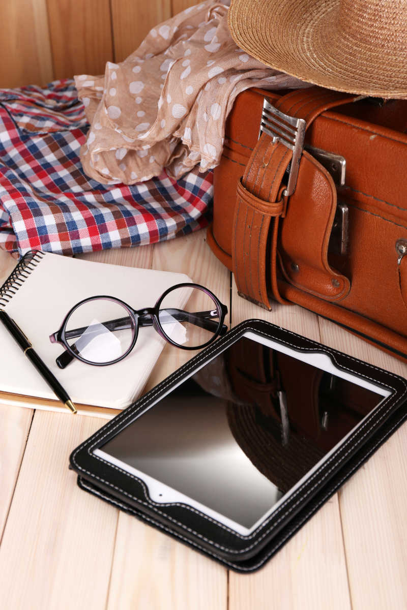 木板上的行李箱和眼镜平板电脑笔本子以及眼镜