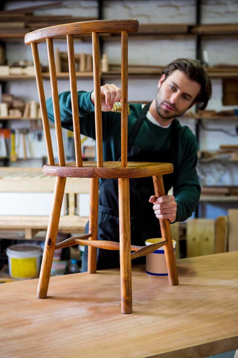 年轻的木匠在为椅子上油漆