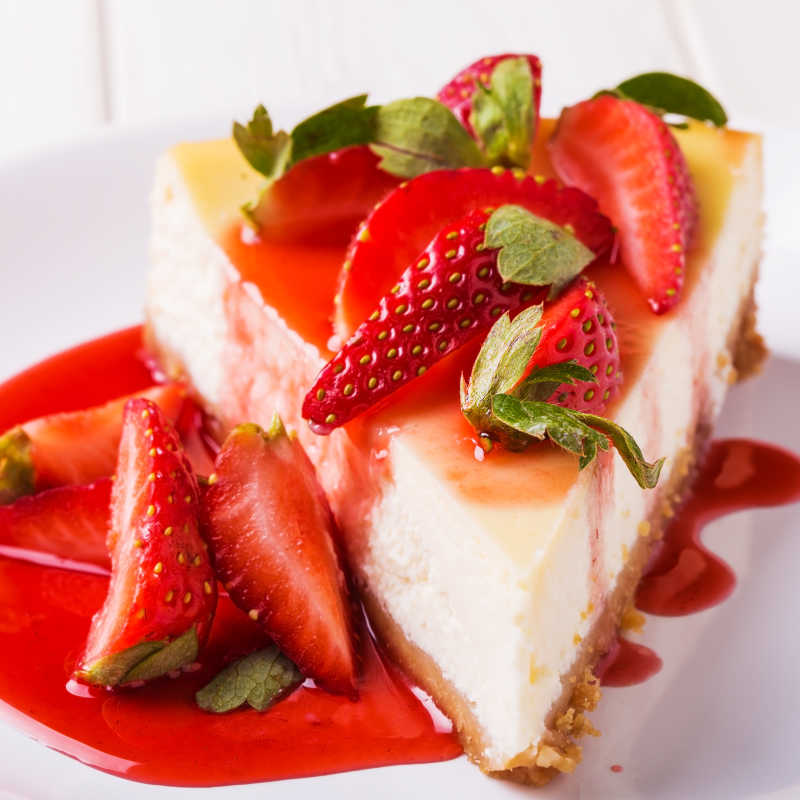 美味的自制芝士蛋糕加上白色的木桌上的草莓