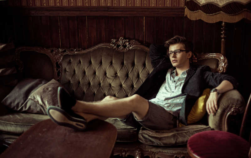 时尚的年轻帅哥坐在沙发上照片