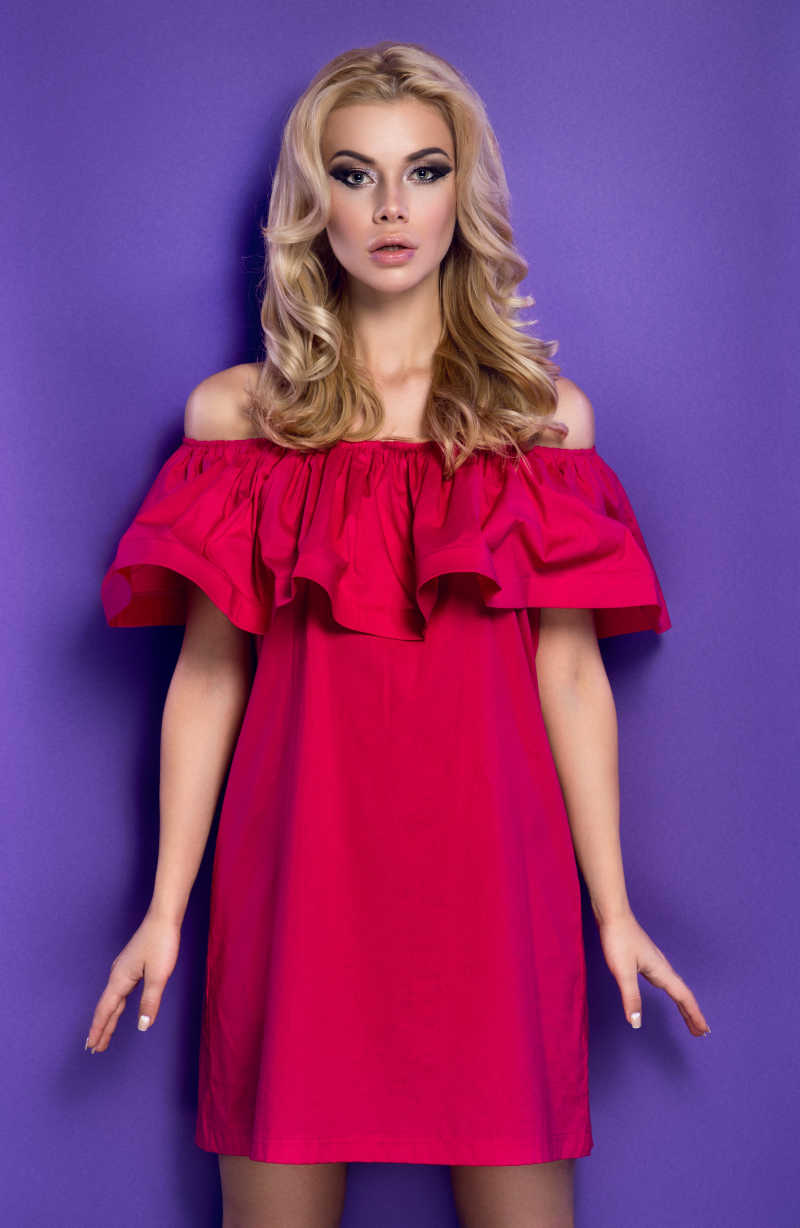紫色背景下穿着红色露肩礼服的金发美女