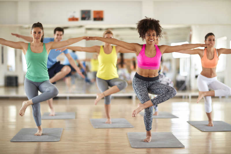 明亮的木地板背景上做瑜伽身体平衡训练的健身团队