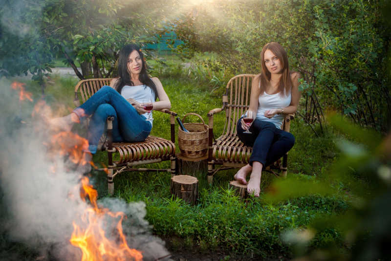 露营的两位美女坐在篝火旁边