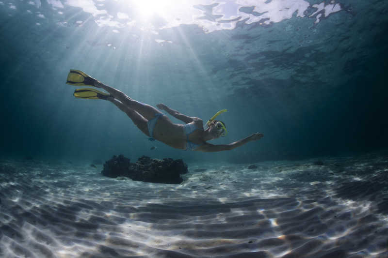 阳光透过海面照到海底以及潜水的女人