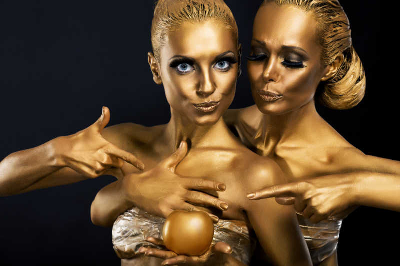 两个展现人体艺术的涂满金色的滑稽女人