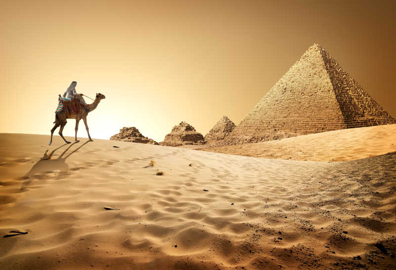 骆驼商人骑在金字塔群旁