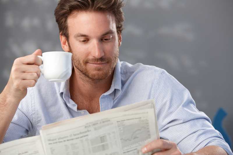 男子喝着咖啡看着报纸