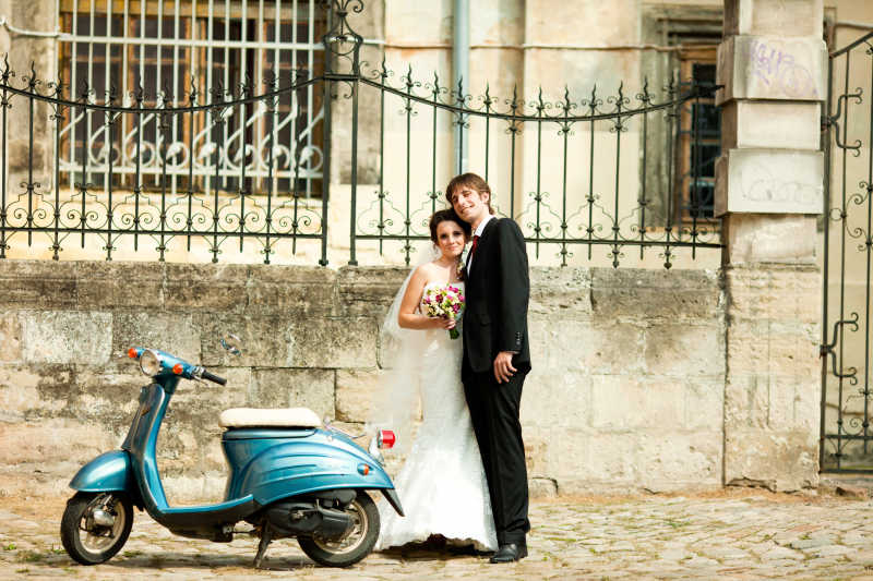 摩托车旁的一对新婚夫妇