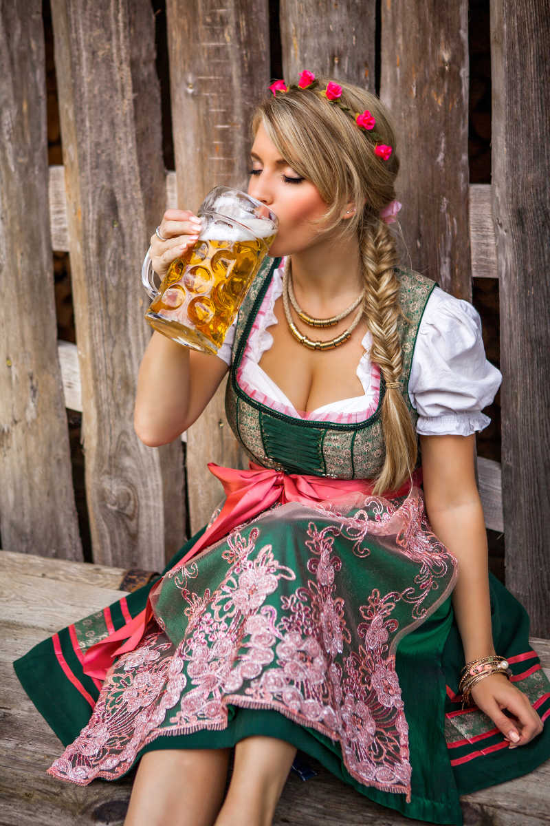 穿着裙子的金发女郎喝啤酒