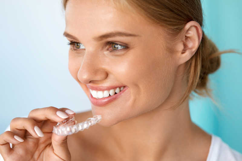 微笑女人用白色牙齿托着牙齿美白托盘