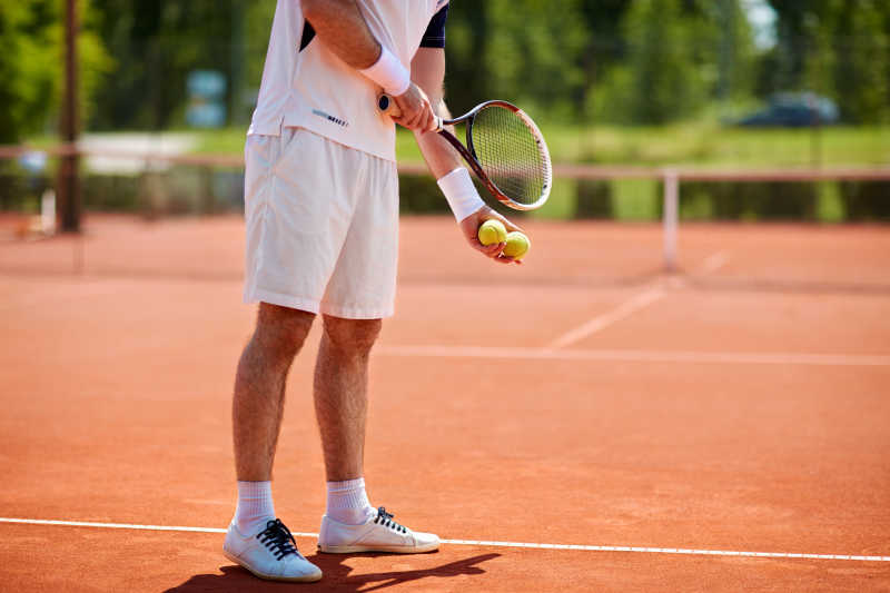 男子网球运动员在红土网球场上发球