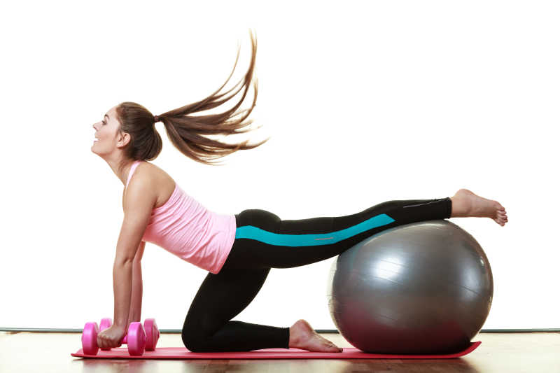 健身房里玩瑜伽球锻炼的年轻女人