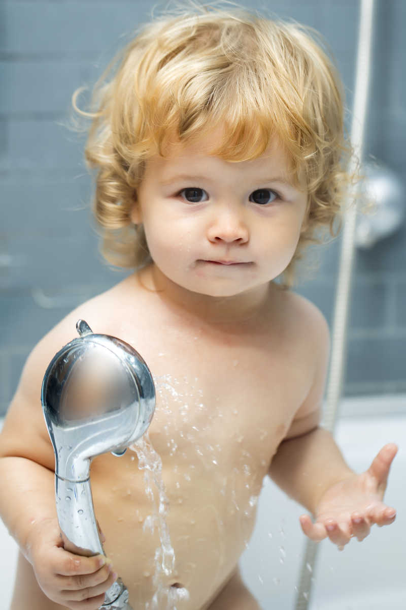 小婴儿拿着淋浴头在洗澡
