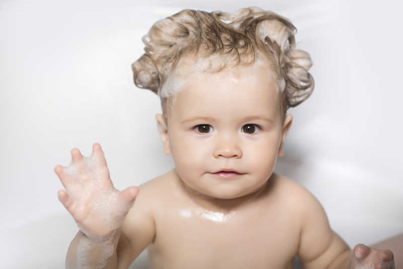 坐在浴缸泡泡里的金发小婴儿