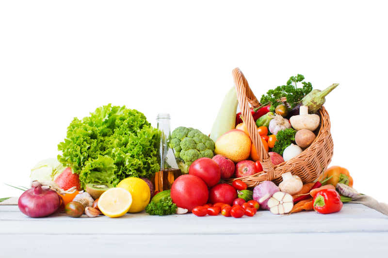 白色背景下的各式各样的水果和柳条筐里的蔬菜