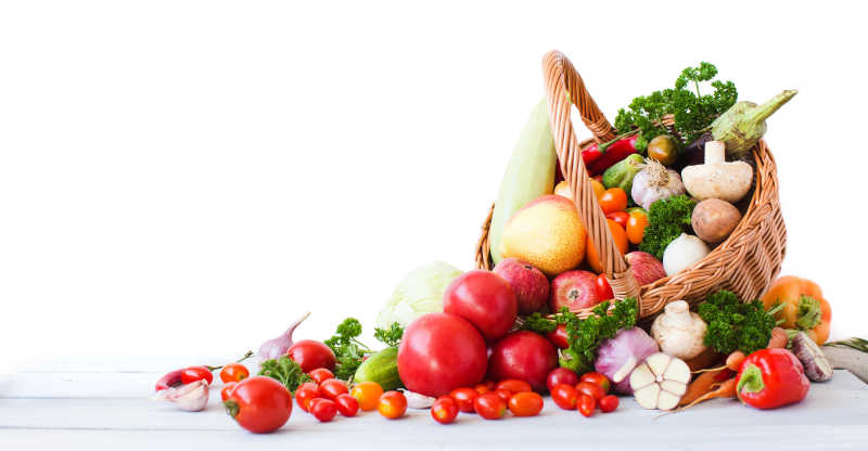 白色背景下色彩缤纷的水果和柳条筐里的蔬菜