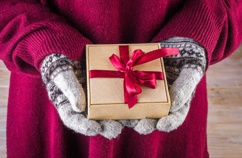 女人戴着冬季手套与圣诞礼品盒