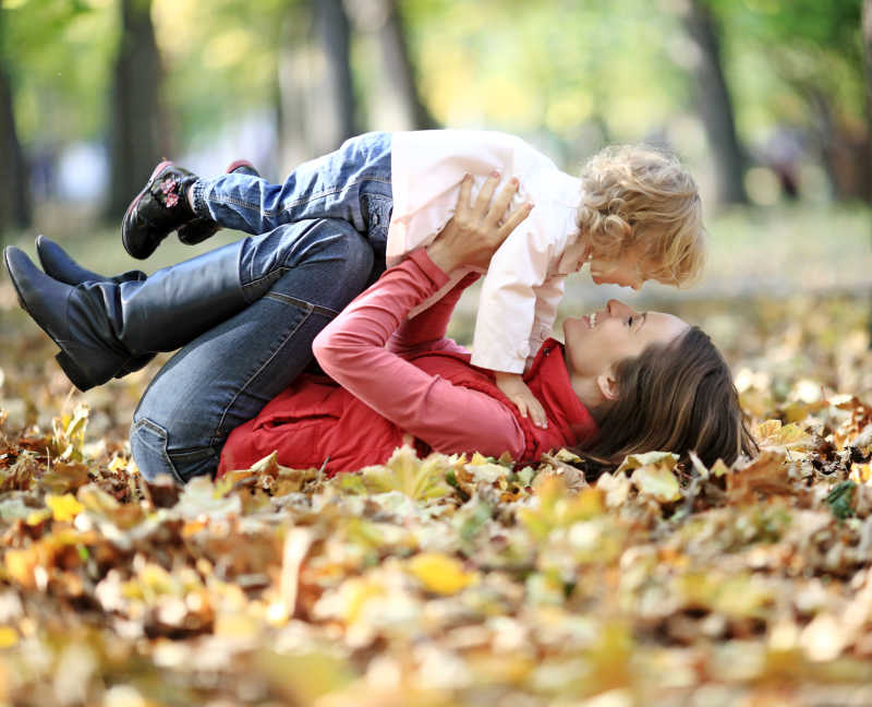 秋季草地上的枯树叶与快乐的母子