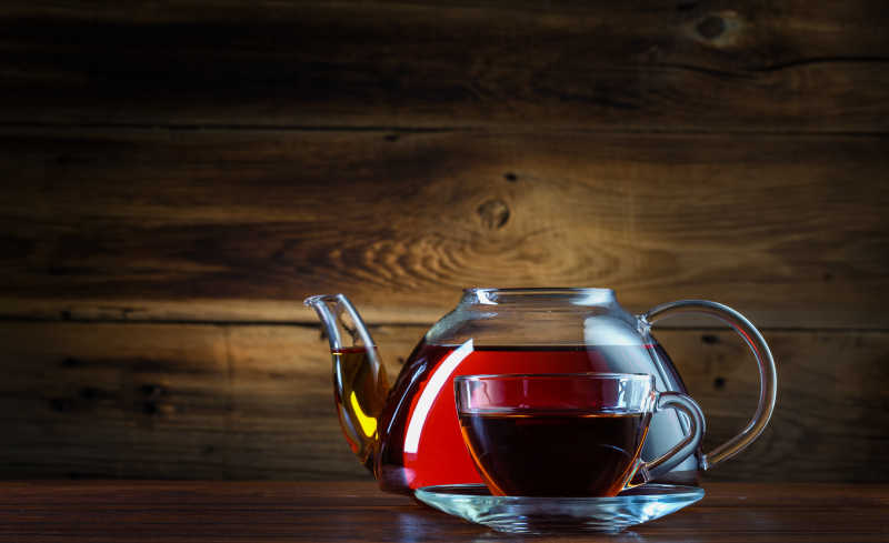 木制背景下的红茶玻璃茶壶和杯子