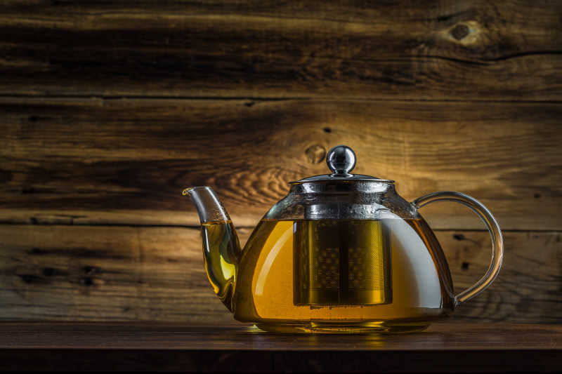 木制背景下的玻璃绿茶茶壶