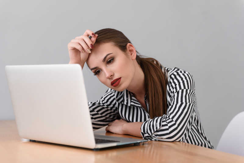 在电脑上工作的精疲力竭的女商人
