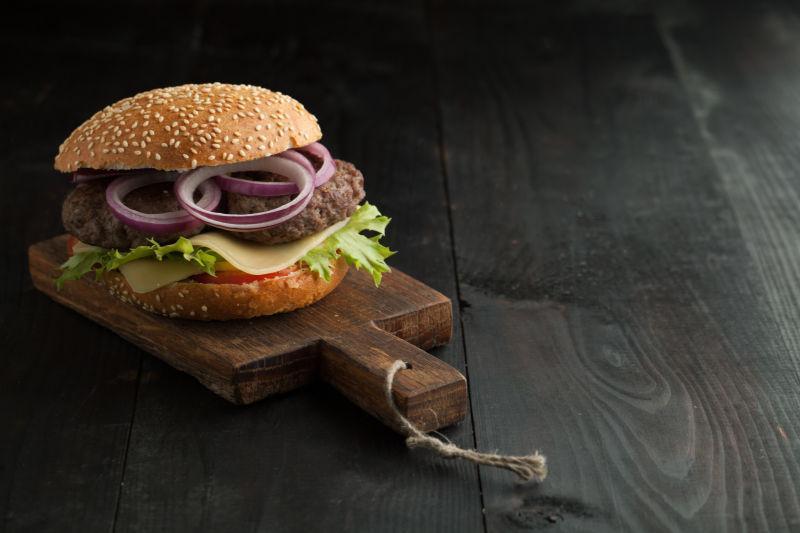 牛肉汉堡和新鲜蔬菜放在木板上