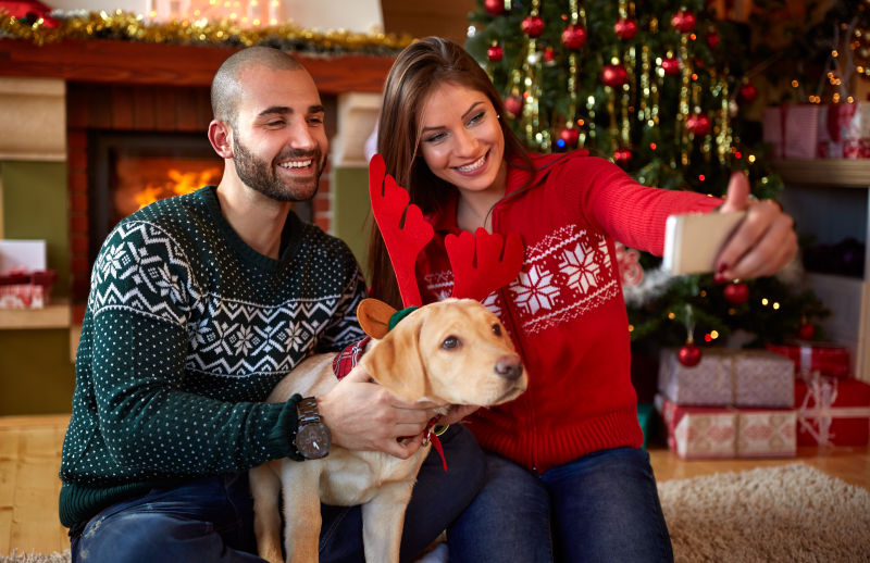 圣诞节年轻情侣抱着狗狗拍照