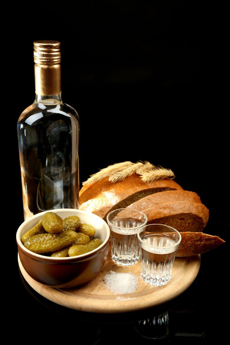 木板上的一瓶酒和面包与腌过的蔬菜