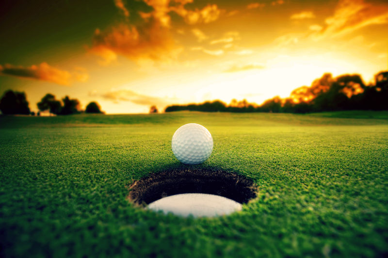 日落时分的高尔夫球洞旁边的高尔夫球