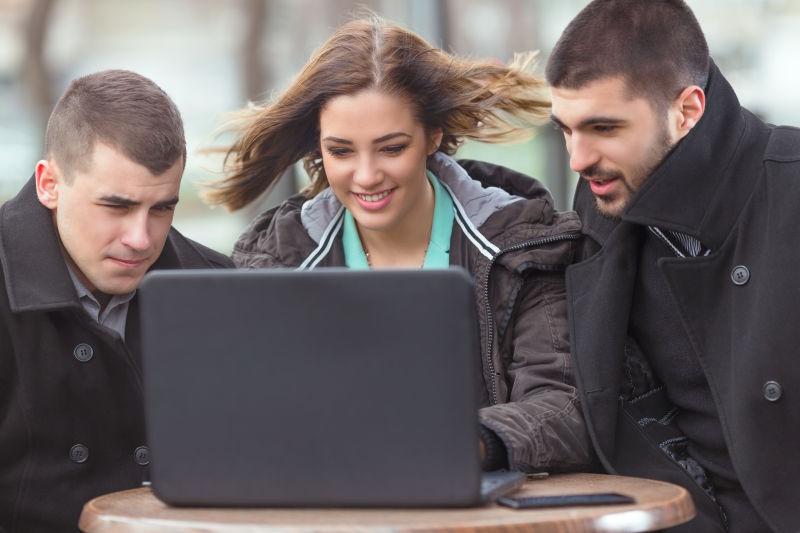三个年轻的大学生在户外咖啡馆使用笔记本