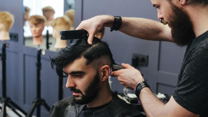 男性理发师在为男子理发