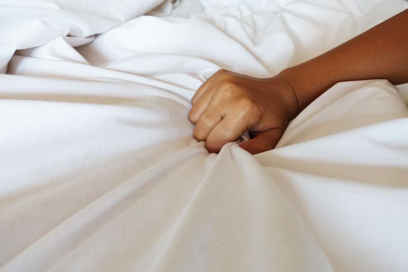 女人的手正拉着白色的床单