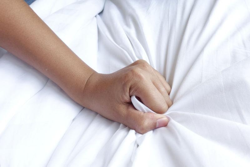 女人的手使劲拉着白色的床单