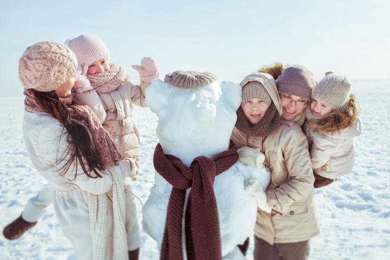 在户外堆雪人的一家人