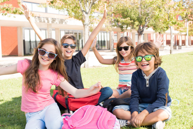 学校里坐在草地上的四个戴墨镜的小学生