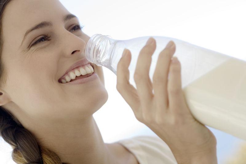 一个年轻女子从瓶子里喝牛奶
