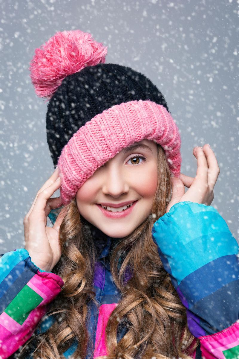 雪中戴着帽子的长着卷发小女孩