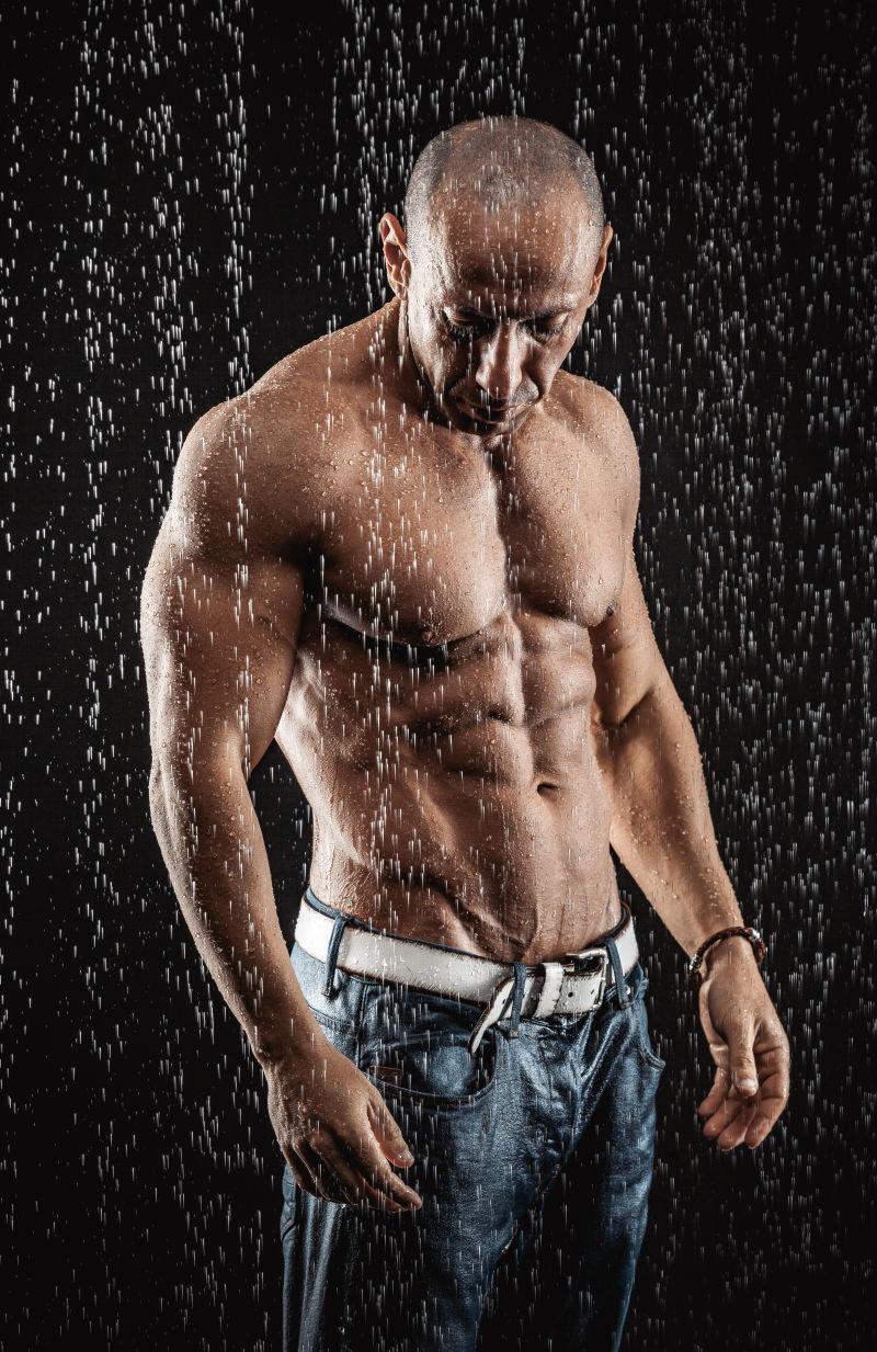 黑色背景前雨中的肌肉男