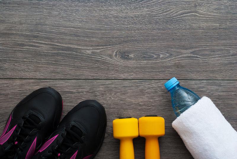 木制地板上的运动鞋哑铃水和毛巾