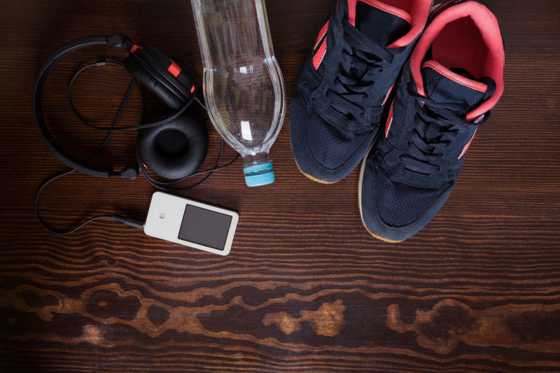 木制背景下的运动鞋水耳机和MP3播放器