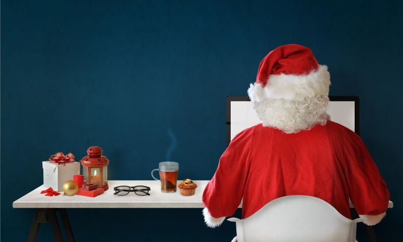 圣诞老人使用电脑的桌子上的热茶