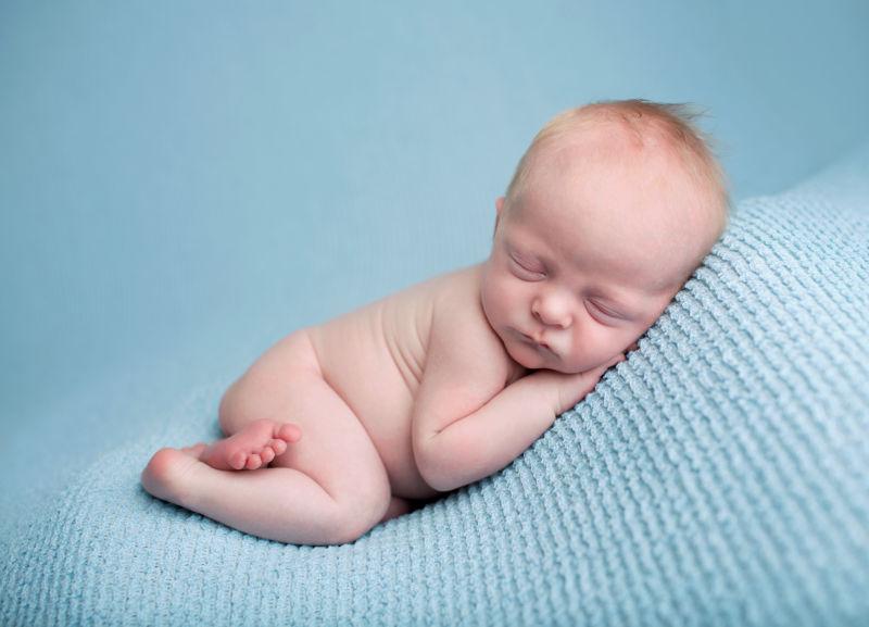 蓝色毯子背景睡着的新生的婴儿
