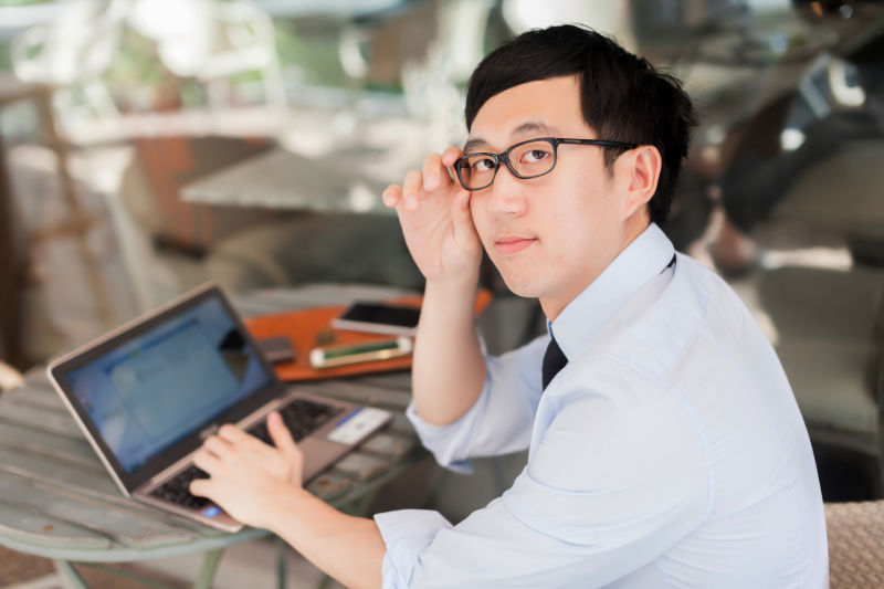 戴眼镜的男人正在用笔记本电脑办公