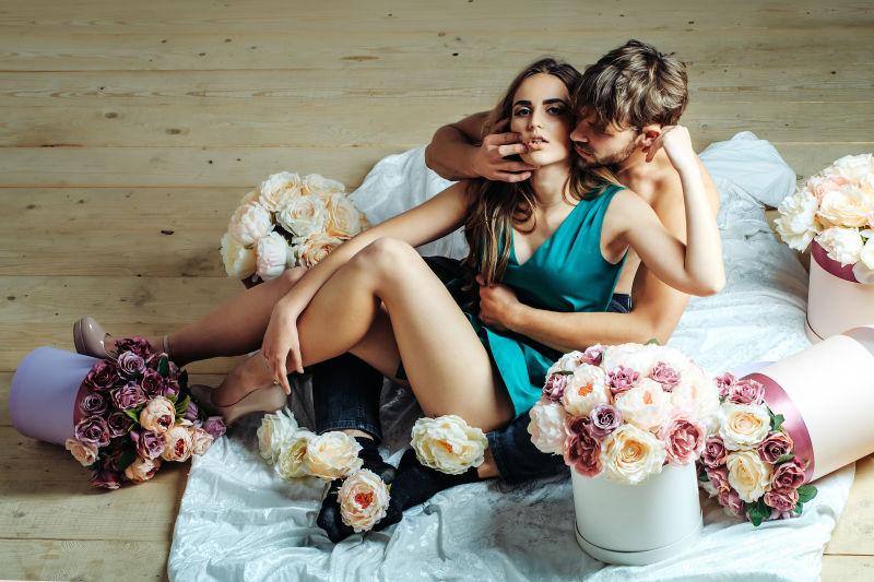 漂亮女孩和性感男人在木板上抱着鲜花