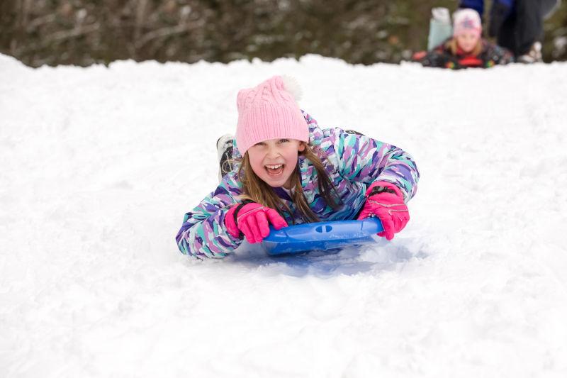 在雪地里玩雪橇的小女孩