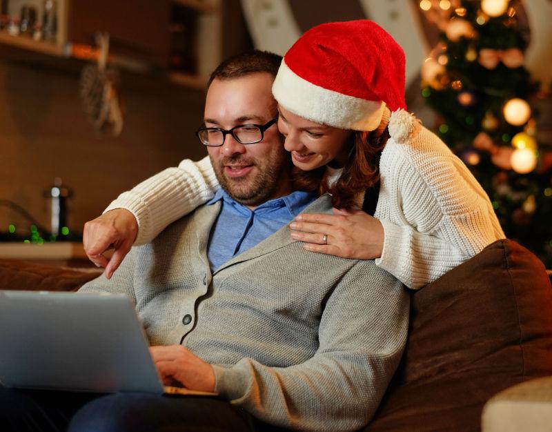 戴着圣诞帽的美女与男人看笔记本电脑