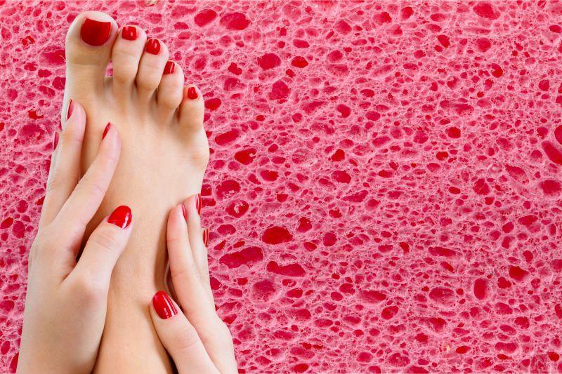 放在粉色泡沫上的涂着红色指甲油的手和脚